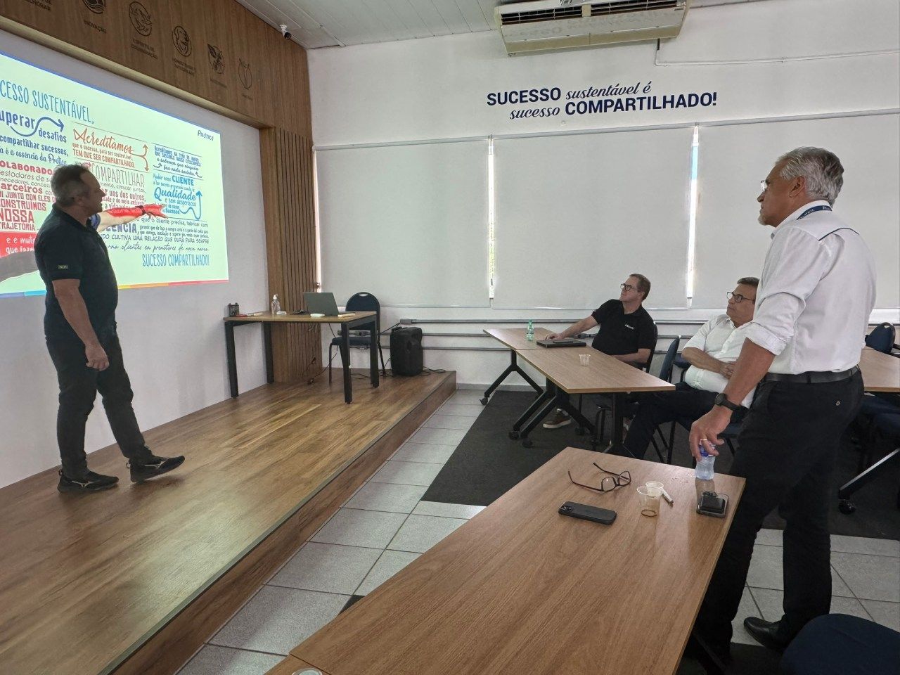 Um homem está fazendo uma apresentação para um grupo de pessoas em uma sala.