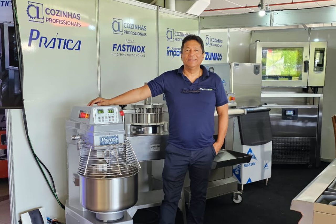 Um homem está parado em frente a um mixer em uma sala.