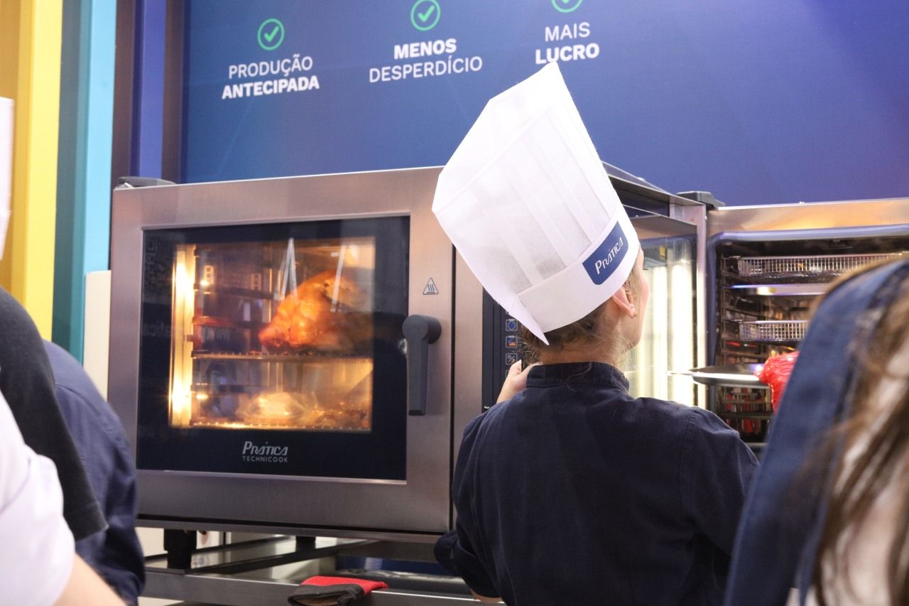 Uma pessoa usando um chapéu de chef está olhando para um forno.
