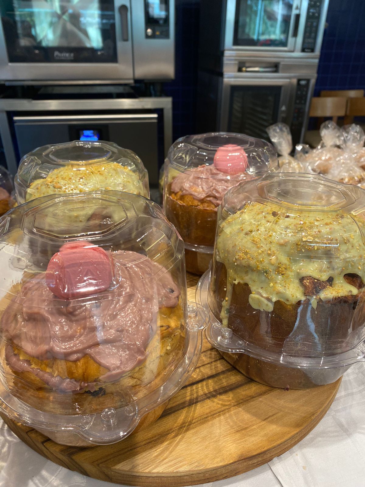 Uma tábua de corte de madeira coberta com cupcakes embrulhados em plástico.