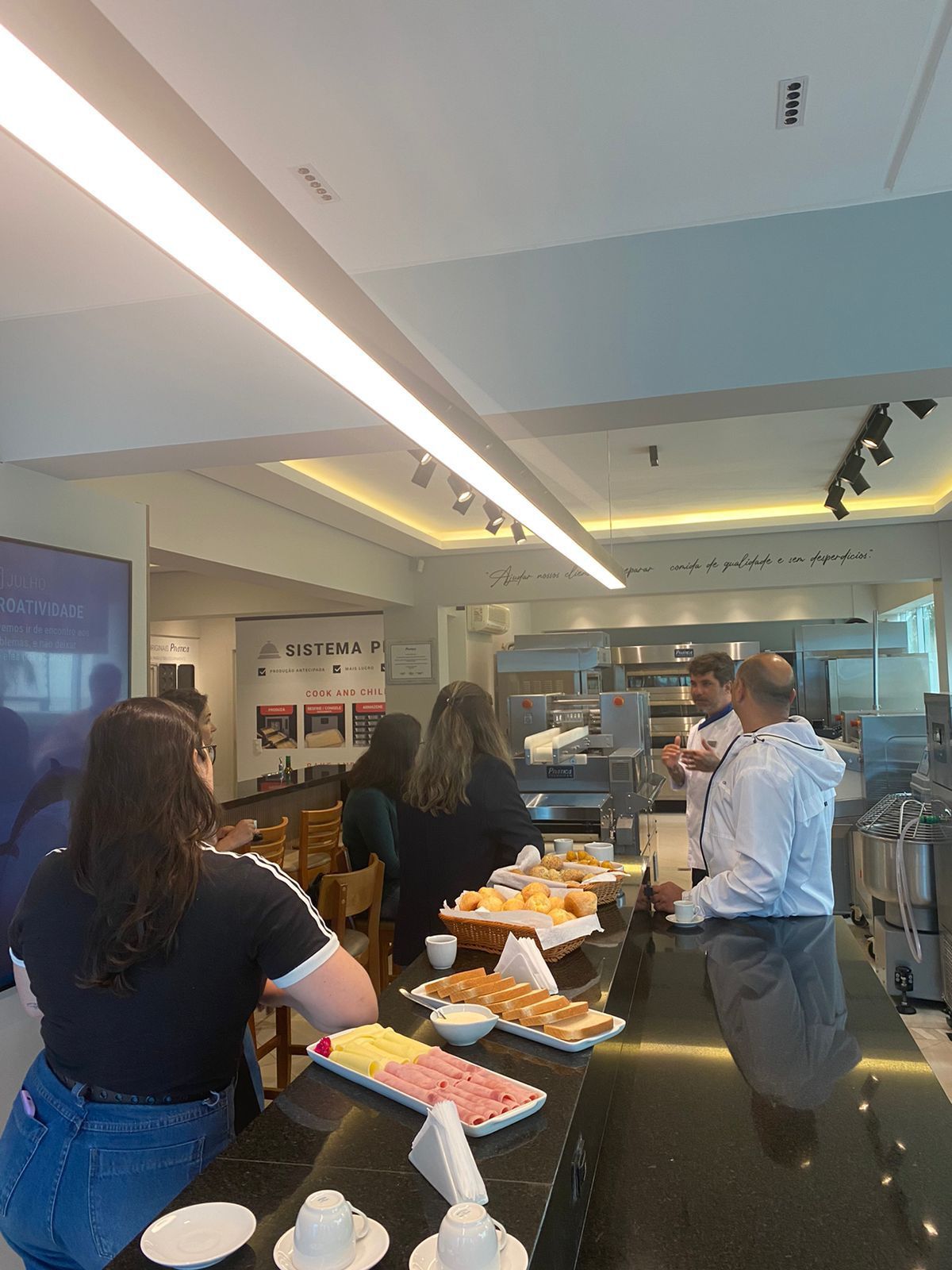 Um grupo de pessoas está em pé ao redor de um balcão em um restaurante.