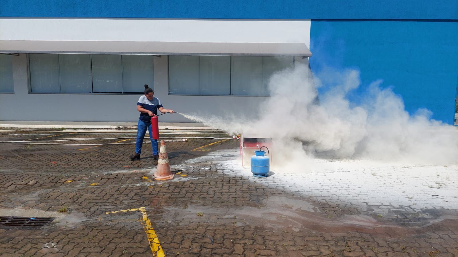 Um homem está usando um extintor de incêndio para apagar um incêndio em um estacionamento.