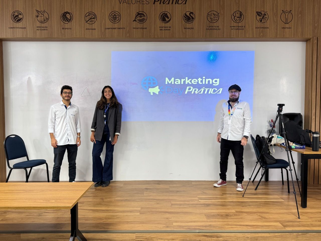 Três pessoas estão em pé diante de uma tela que exibe 