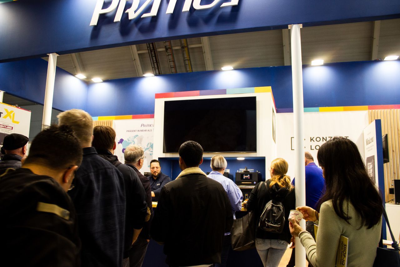 Um grupo de pessoas está em volta de um estande em uma convenção.