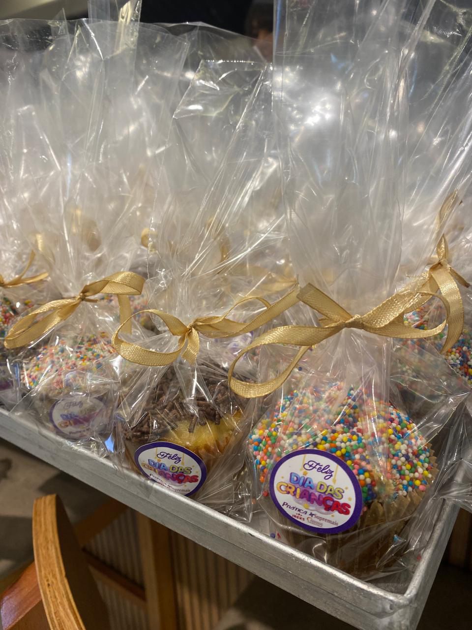 Uma bandeja de cupcakes embrulhados em plástico com granulados por cima.