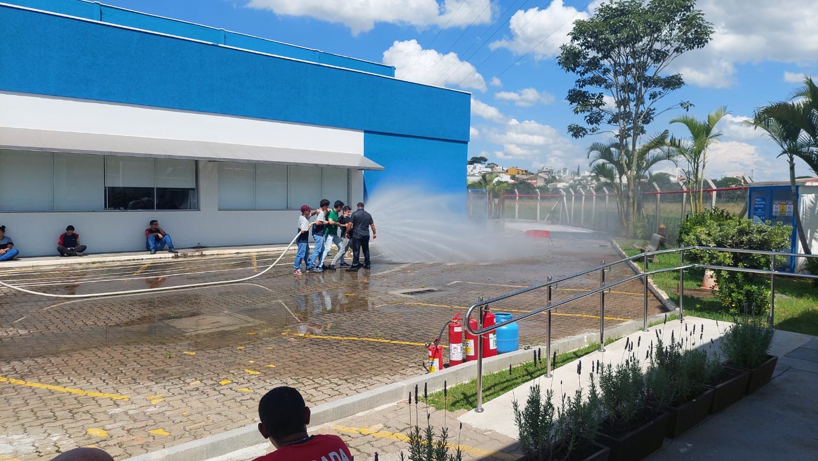Um grupo de pessoas está em pé em frente a um prédio azul.