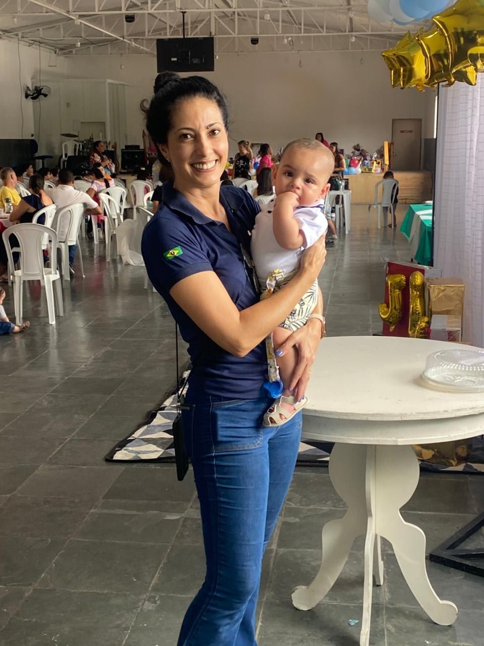 Uma mulher está segurando um bebê nos braços em frente a uma mesa.