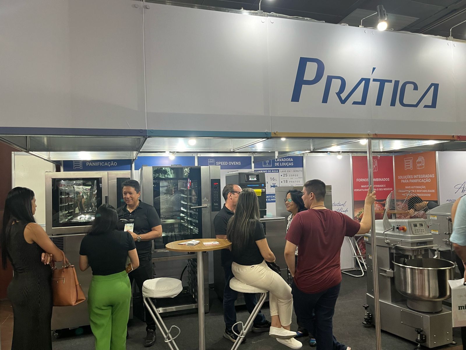 Um grupo de pessoas está em volta de um estande em uma convenção.