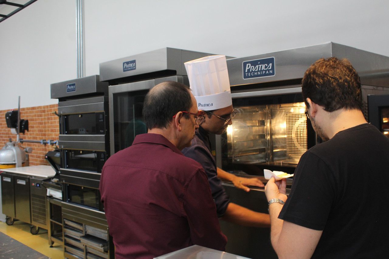 Um homem usando um chapéu de chef está olhando para um forno.