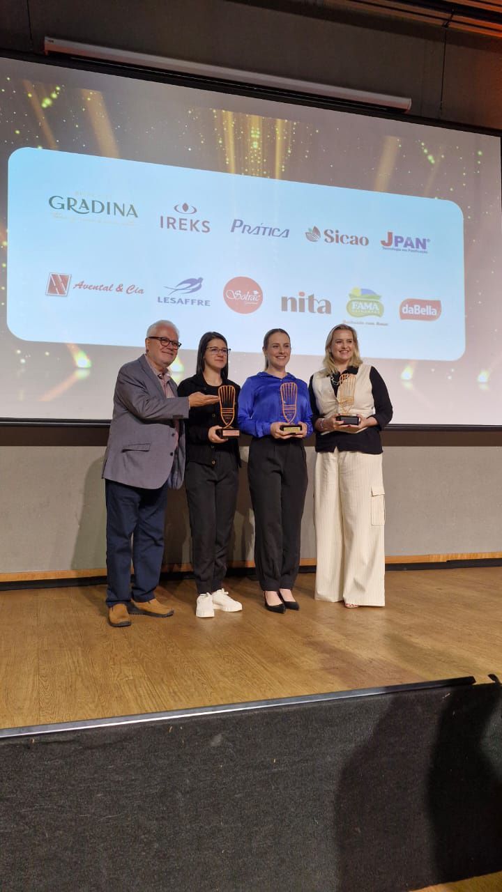 Um grupo de pessoas está em um palco segurando troféus.