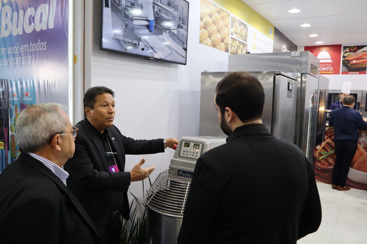 Um grupo de homens está olhando para uma máquina em uma cozinha.