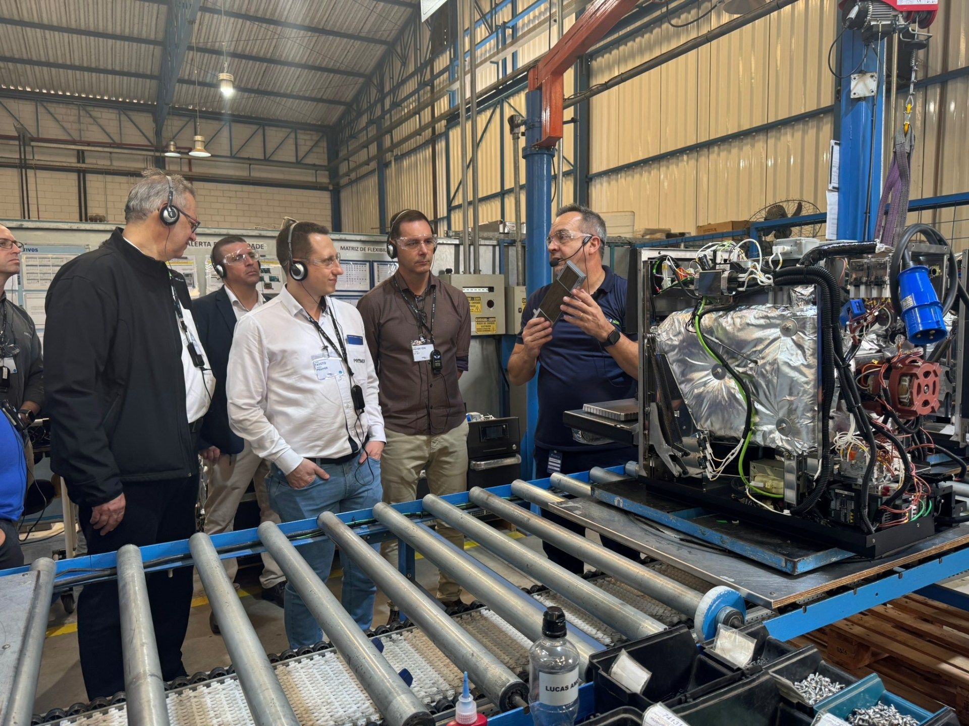 Um grupo de homens está em volta de uma máquina em uma fábrica.