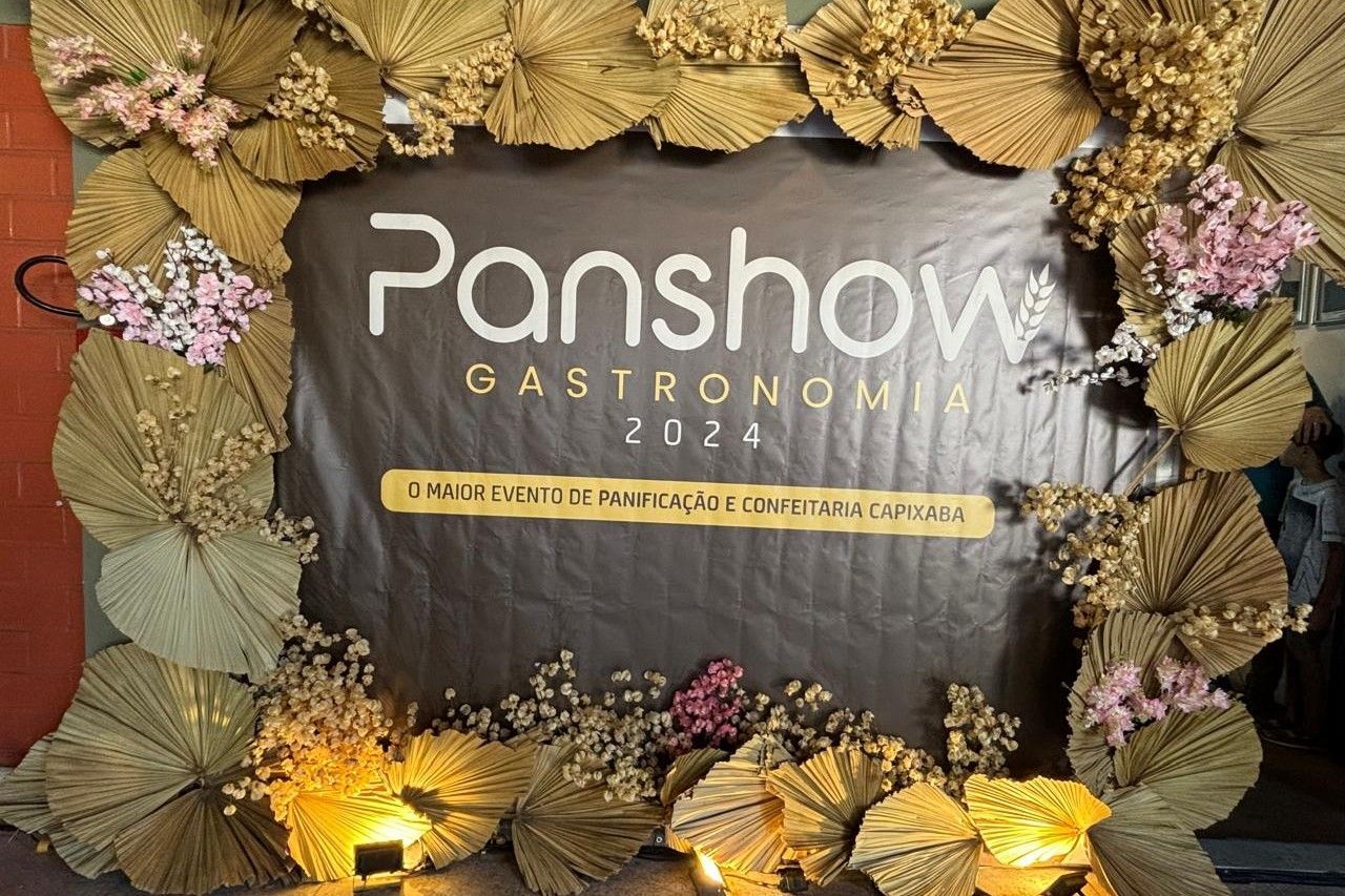 Uma placa do panshow gastronomia está cercada por flores e folhas secas.