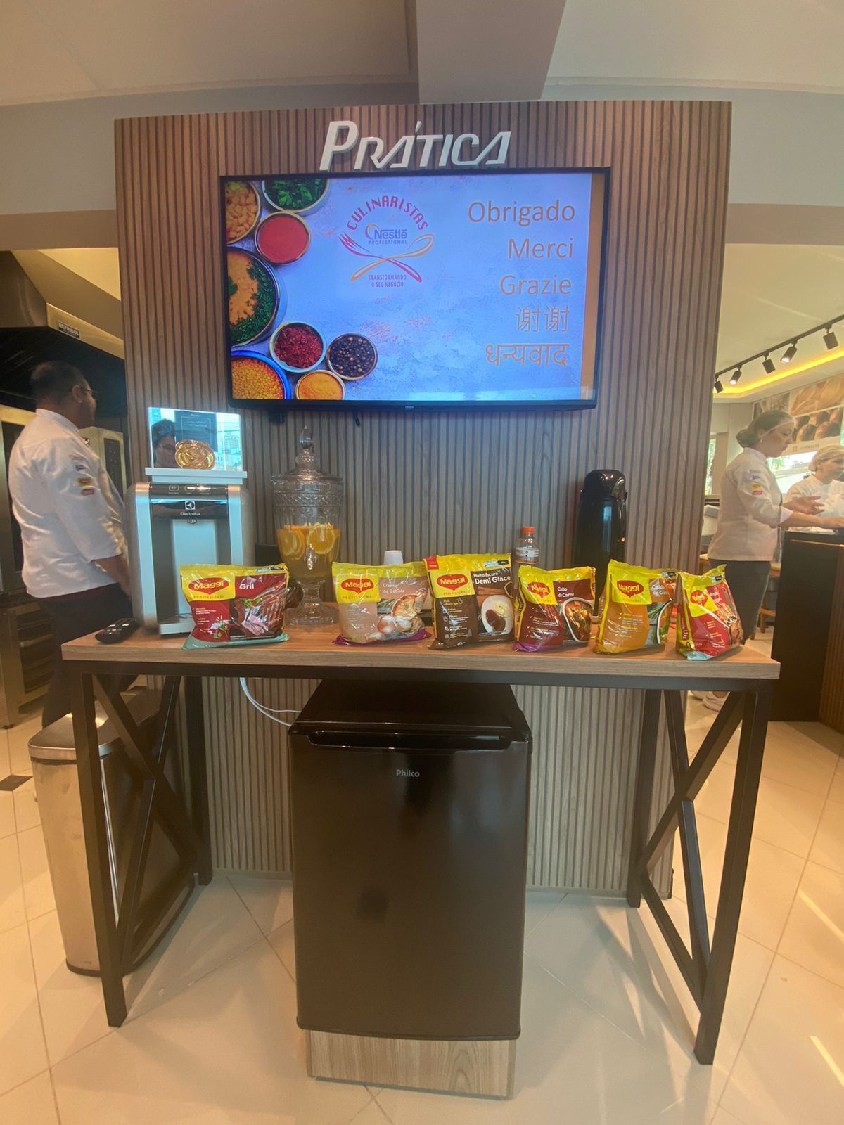 Uma mesa com muita comida e uma TV na parede.