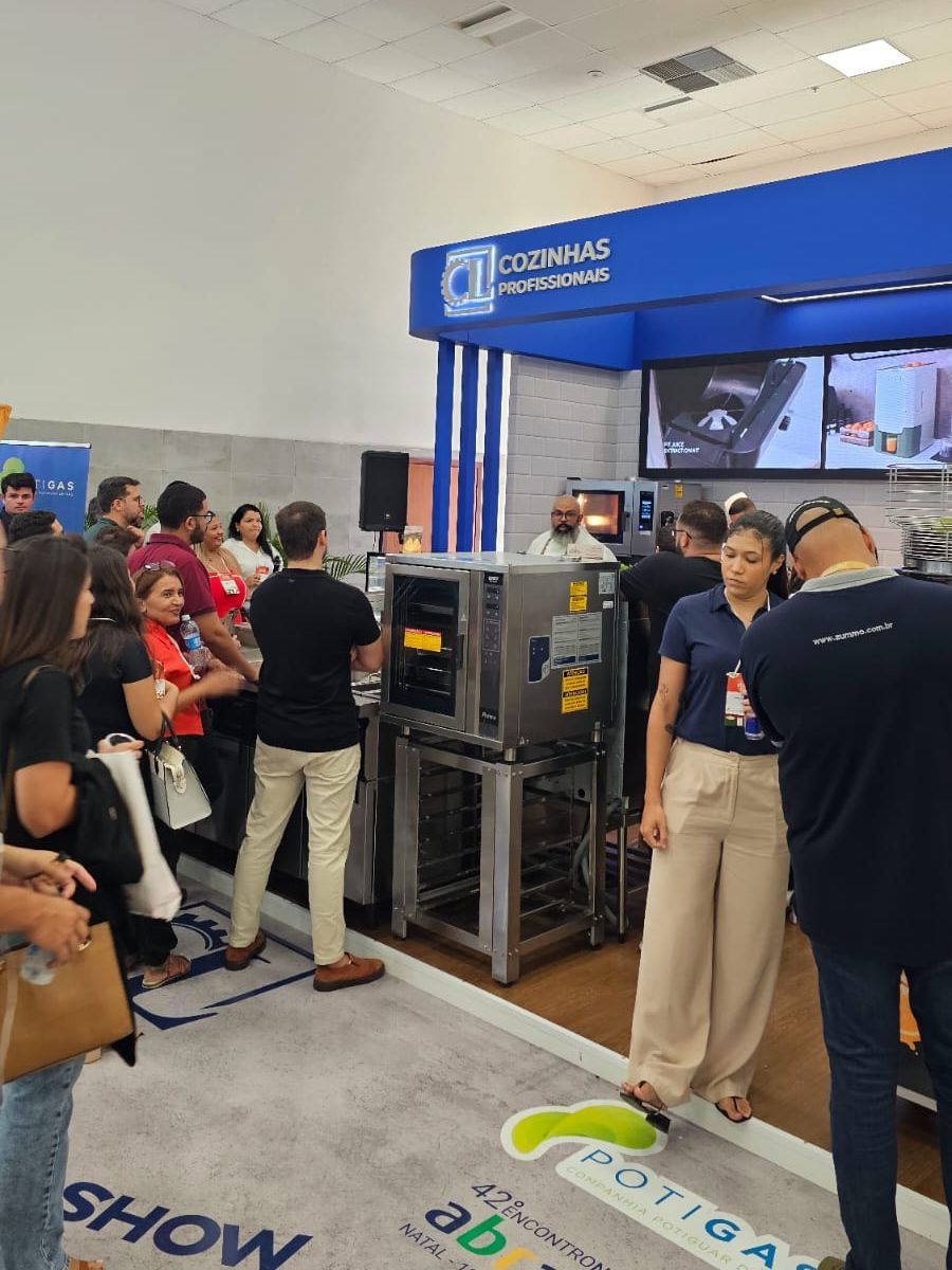 Um grupo de pessoas está em uma sala olhando para uma máquina.