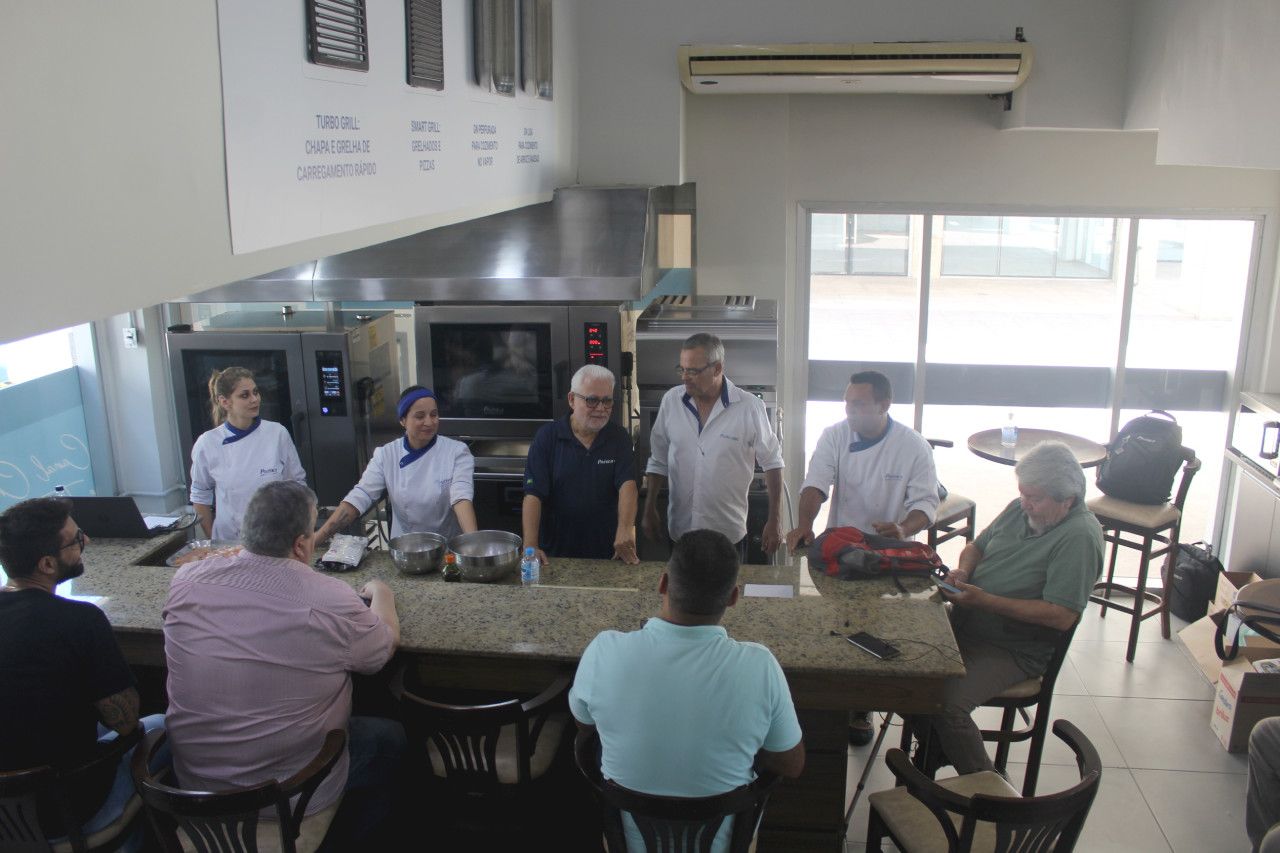 Um grupo de pessoas está sentado ao redor de uma mesa na cozinha.