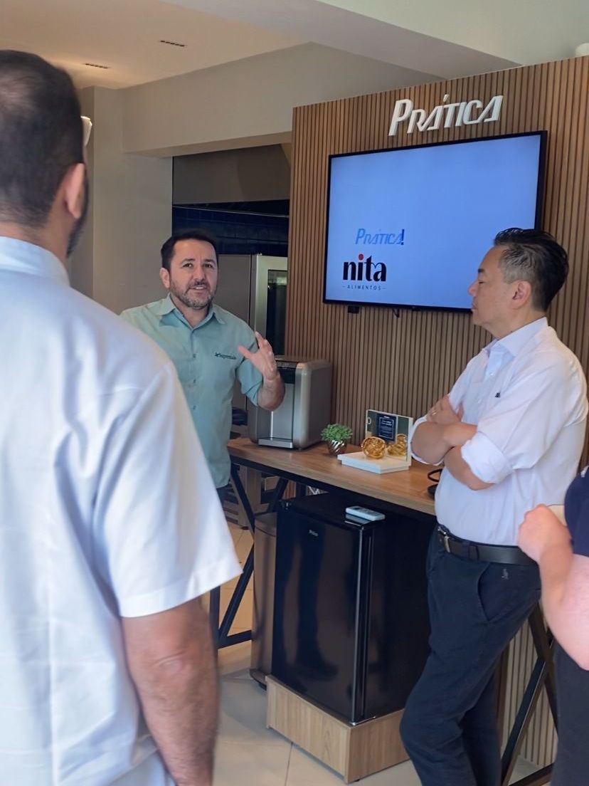 Um grupo de homens está parado em frente a uma tv que diz nita