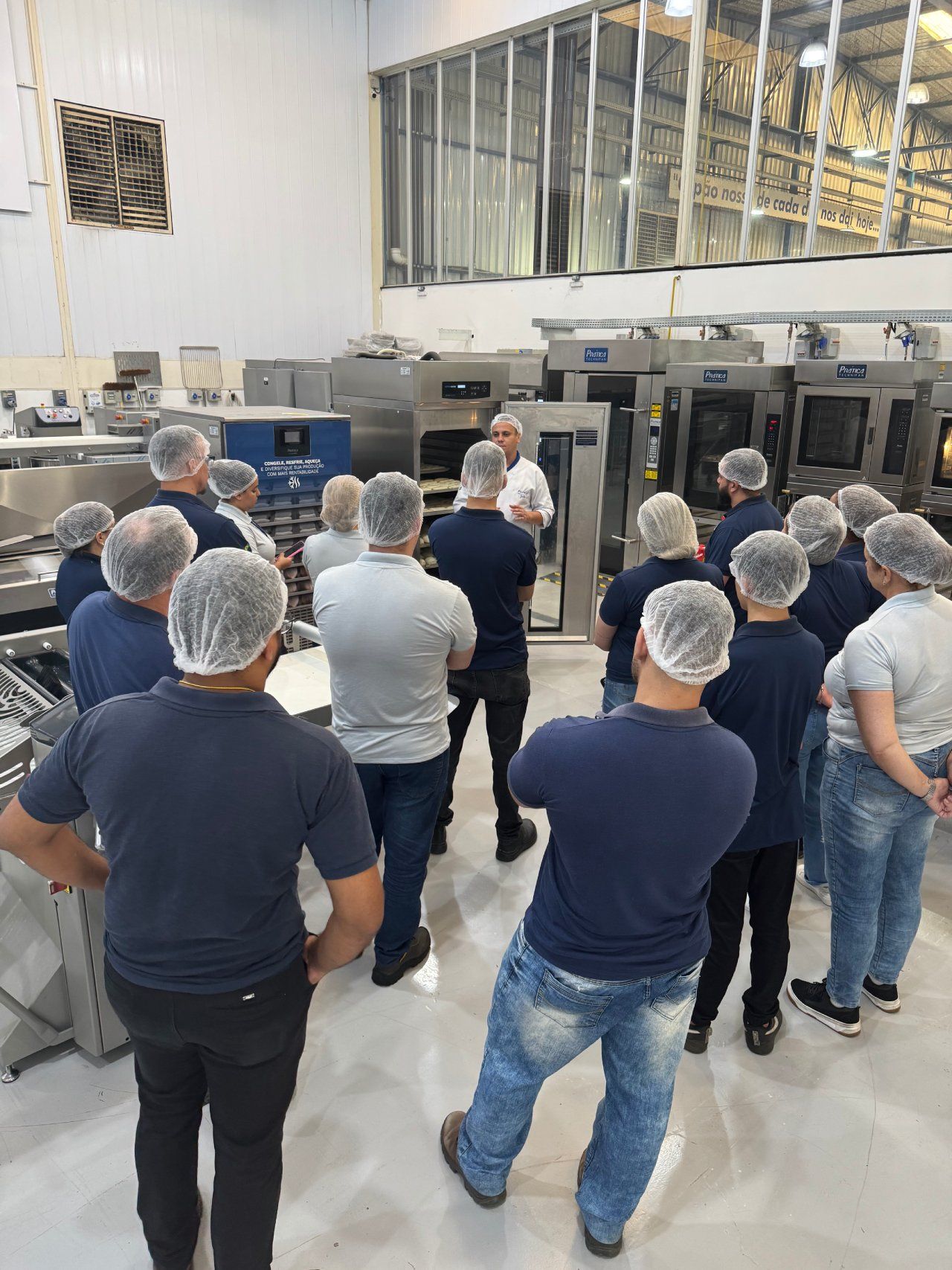 Um grupo de pessoas usando redes de cabelo estão em uma cozinha.