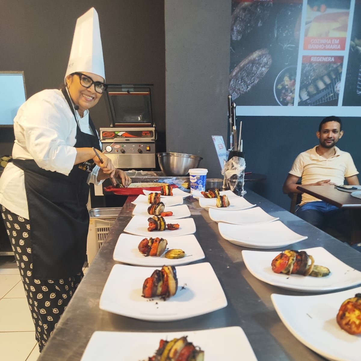 Uma mulher com chapéu de chef está preparando comida em uma mesa