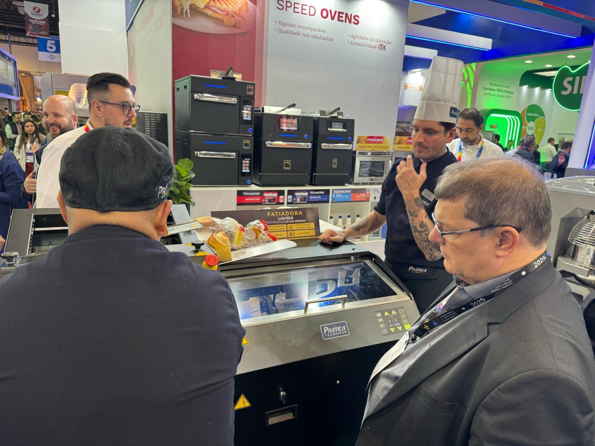 Um grupo de homens está olhando para uma máquina em um programa de culinária.