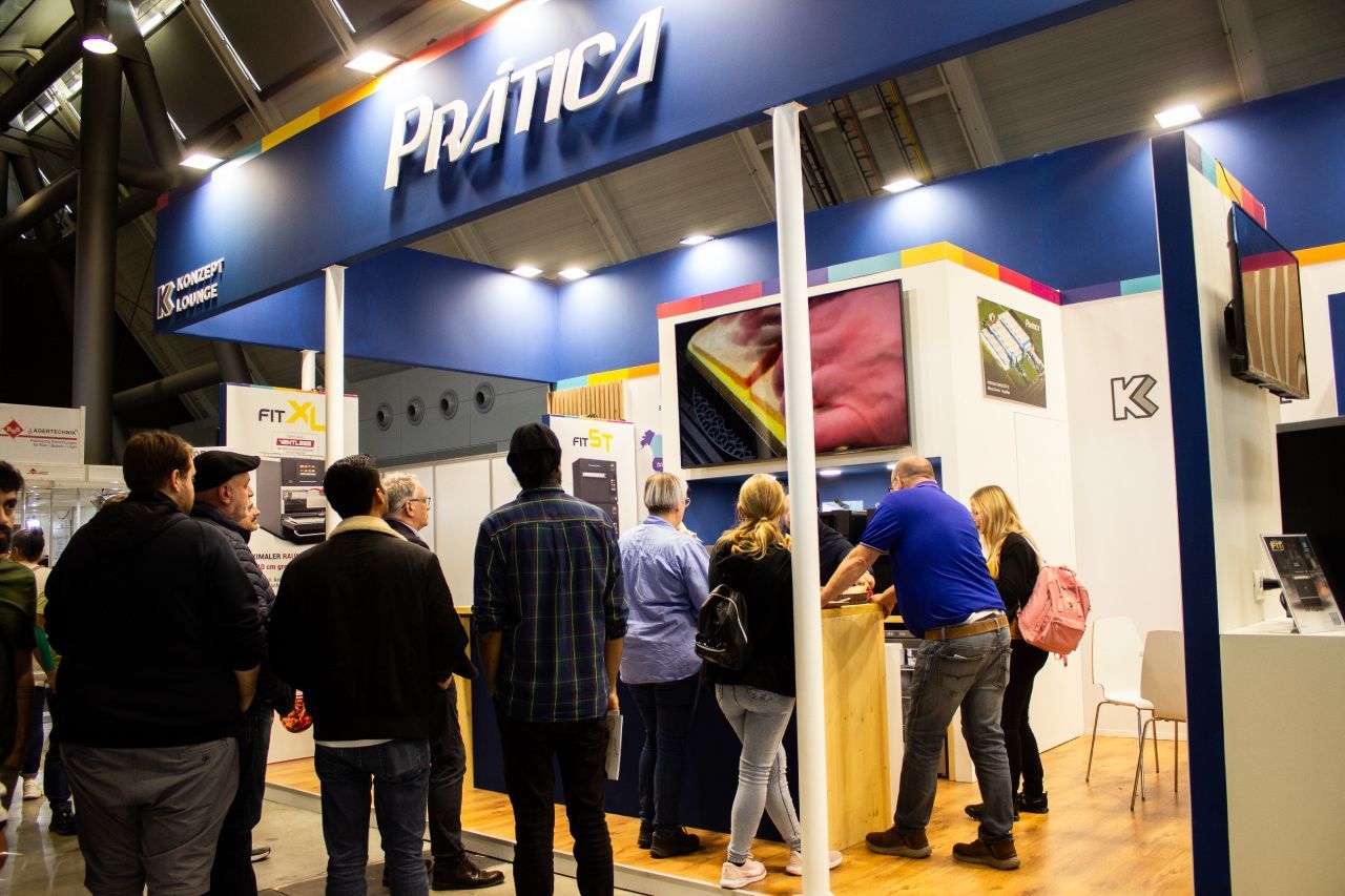 Um grupo de pessoas está em frente a um estande em uma convenção.
