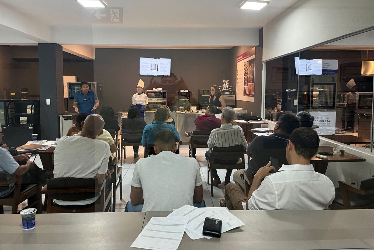 Um grupo de pessoas está sentado em mesas em uma sala.