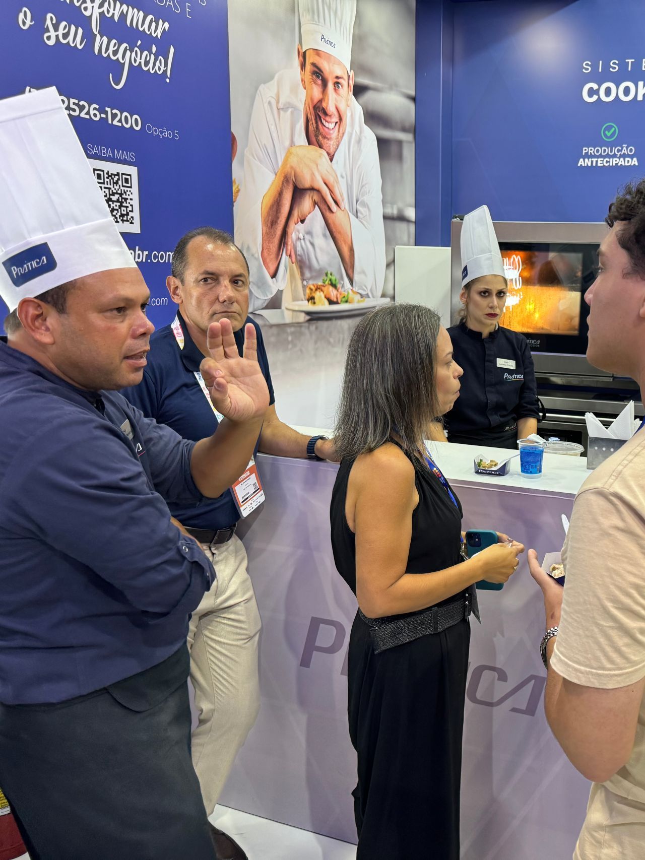 Um grupo de pessoas usando chapéus de chef estão em uma sala