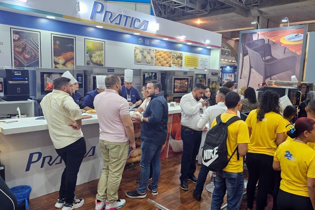 Um grupo de pessoas está em pé ao redor de um balcão em um restaurante.