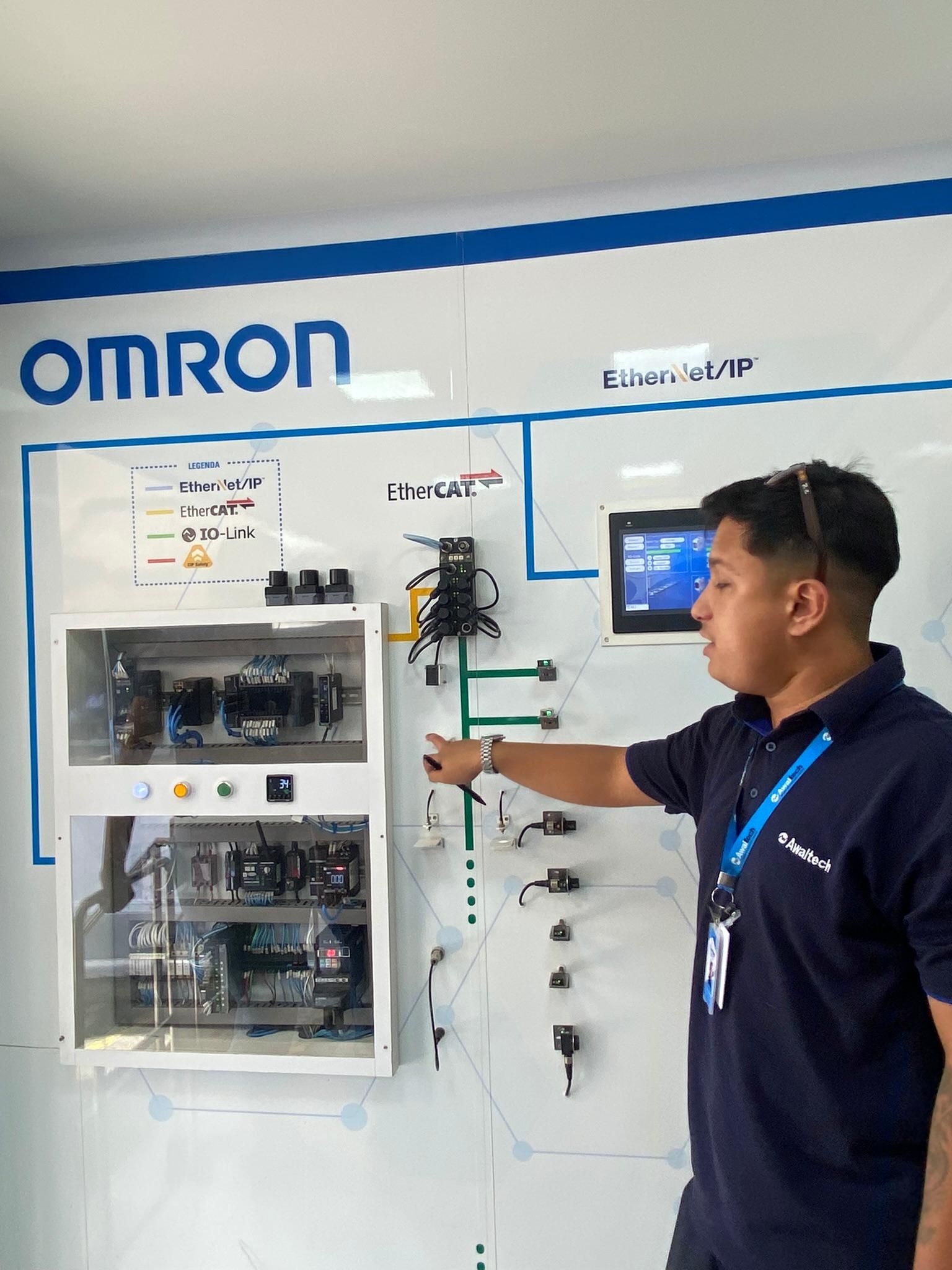 Um homem está de pé em frente a um quadro branco com a palavra omron escrita nele.