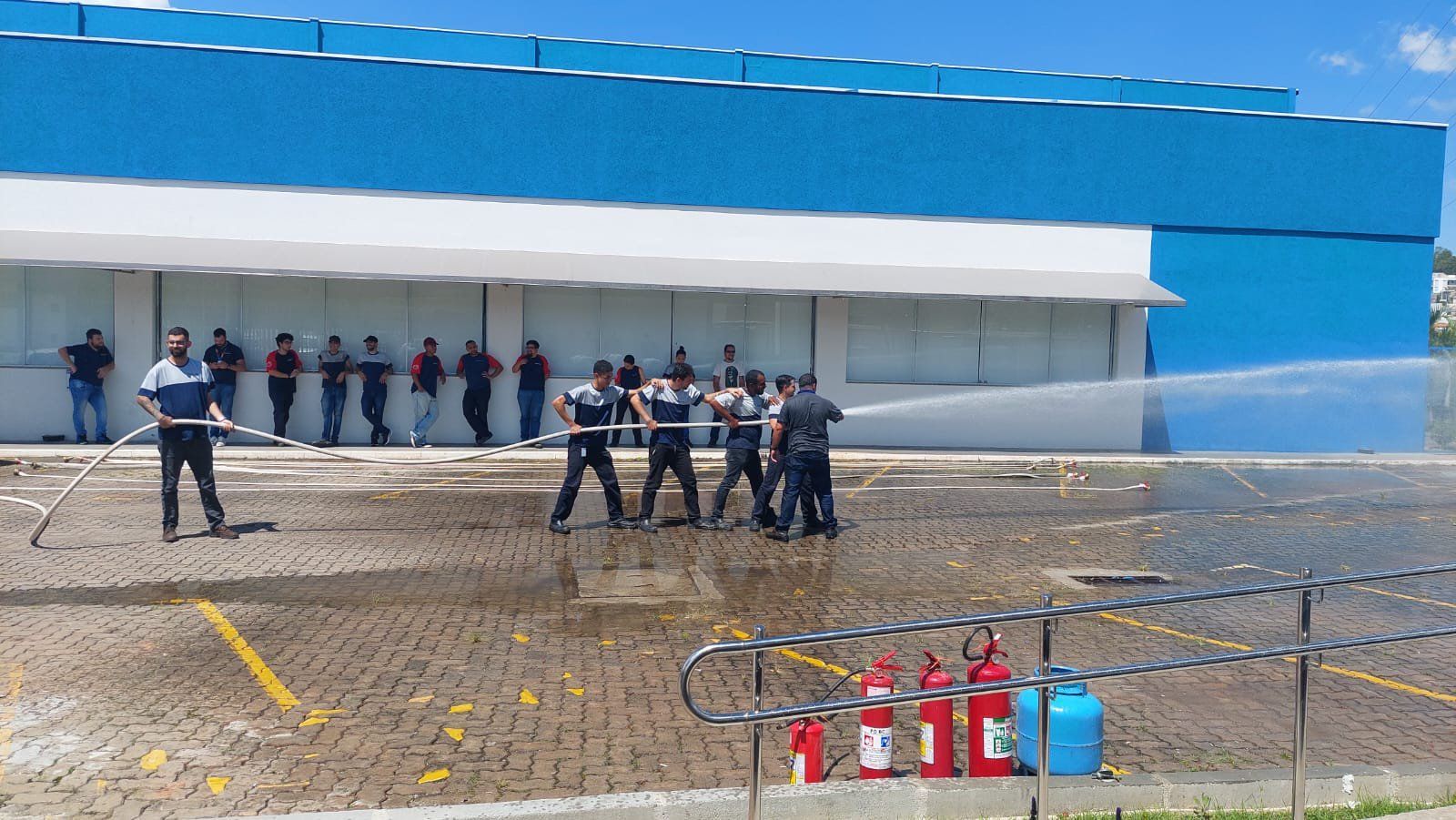 Um grupo de pessoas está em frente a um prédio borrifando água.