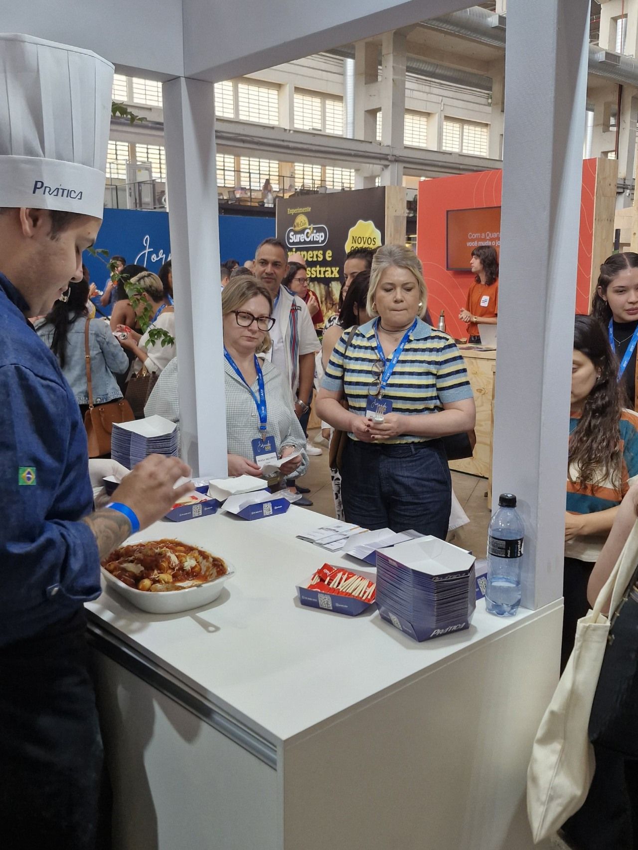Um homem com chapéu de chef está servindo comida para um grupo de pessoas.