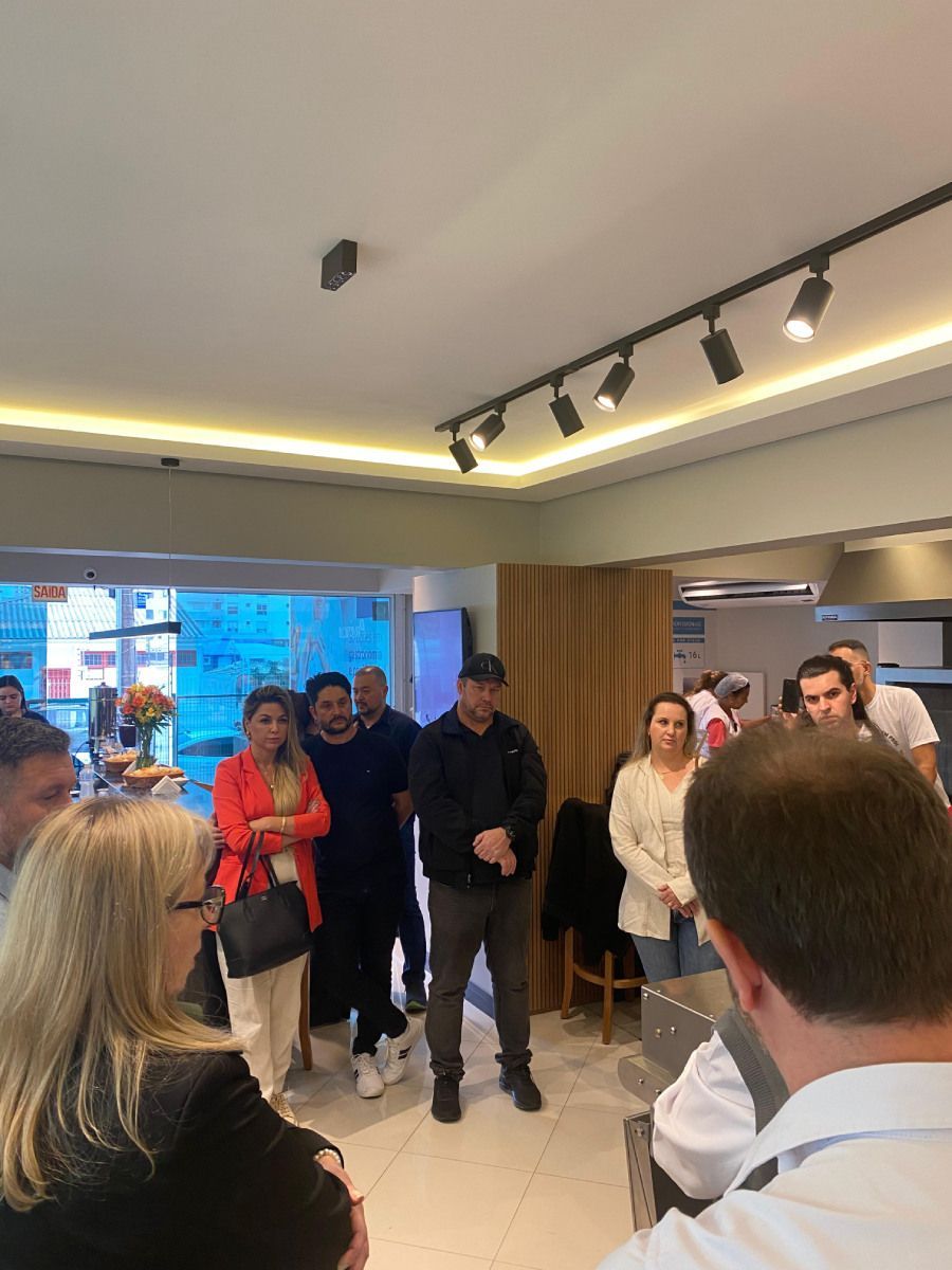 Um grupo de pessoas está em pé em uma sala com luzes no teto.