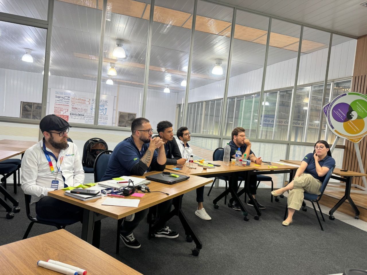 Seis pessoas estão sentadas ao redor de uma mesa de madeira