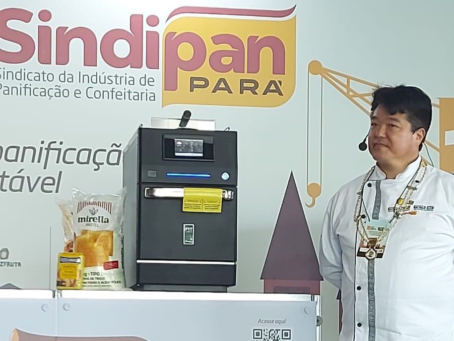 Um homem está em frente a uma placa que diz sindipan para