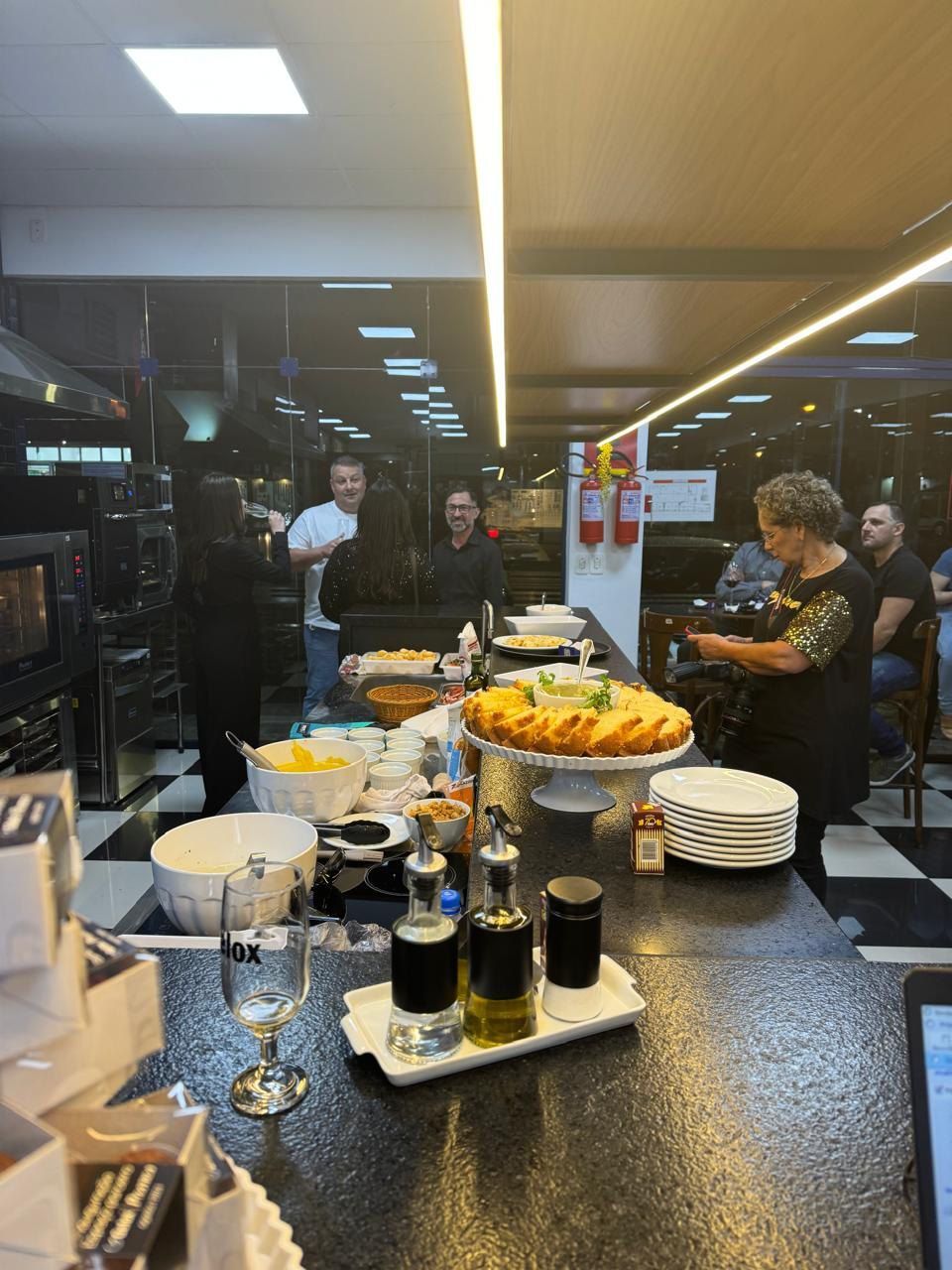 Um grupo de pessoas está em pé ao redor de uma mesa com comida.