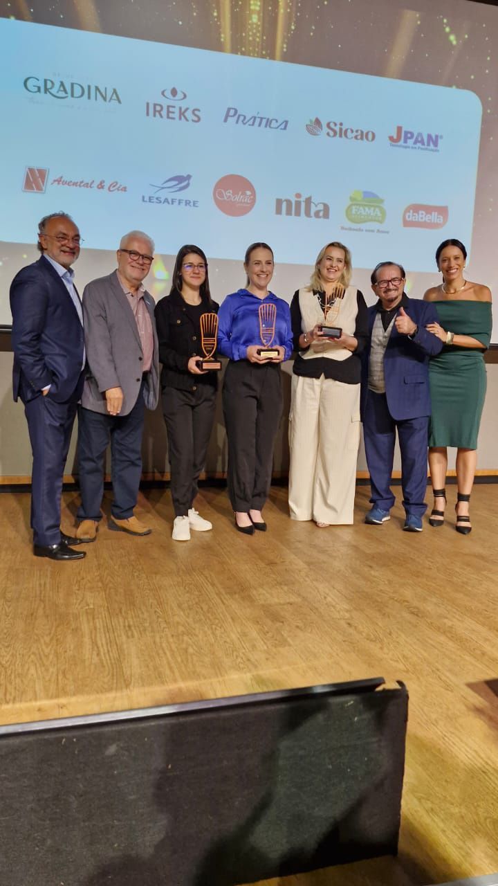 Um grupo de pessoas em pé em um palco segurando troféus