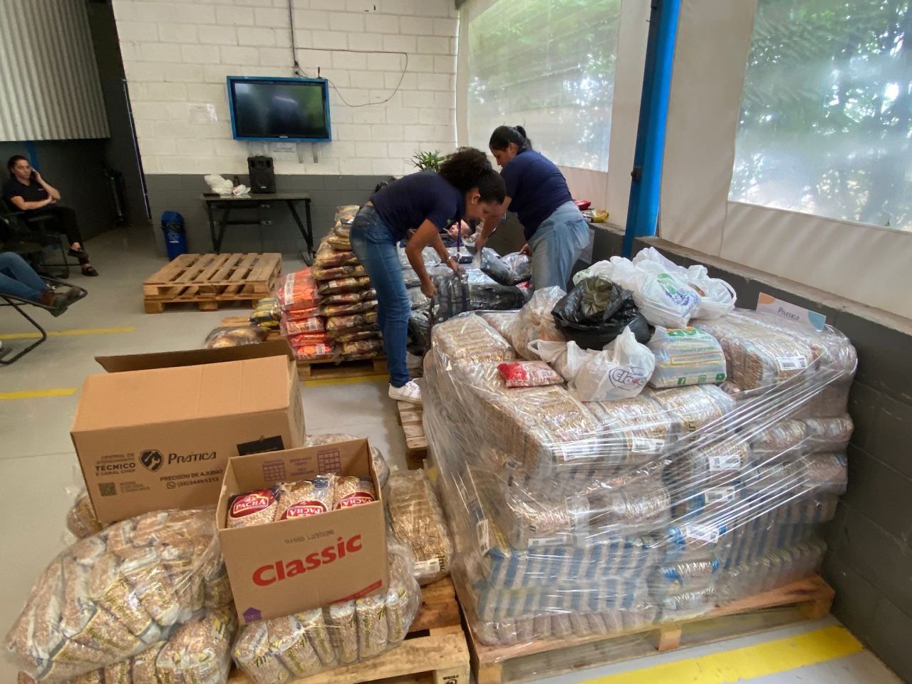 Um grupo de pessoas está trabalhando em uma grande pilha de comida em um armazém.