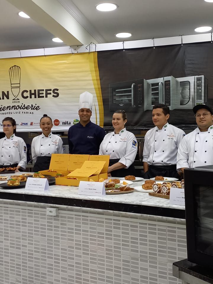 Um grupo de chefs está em frente a uma placa que diz n chefs