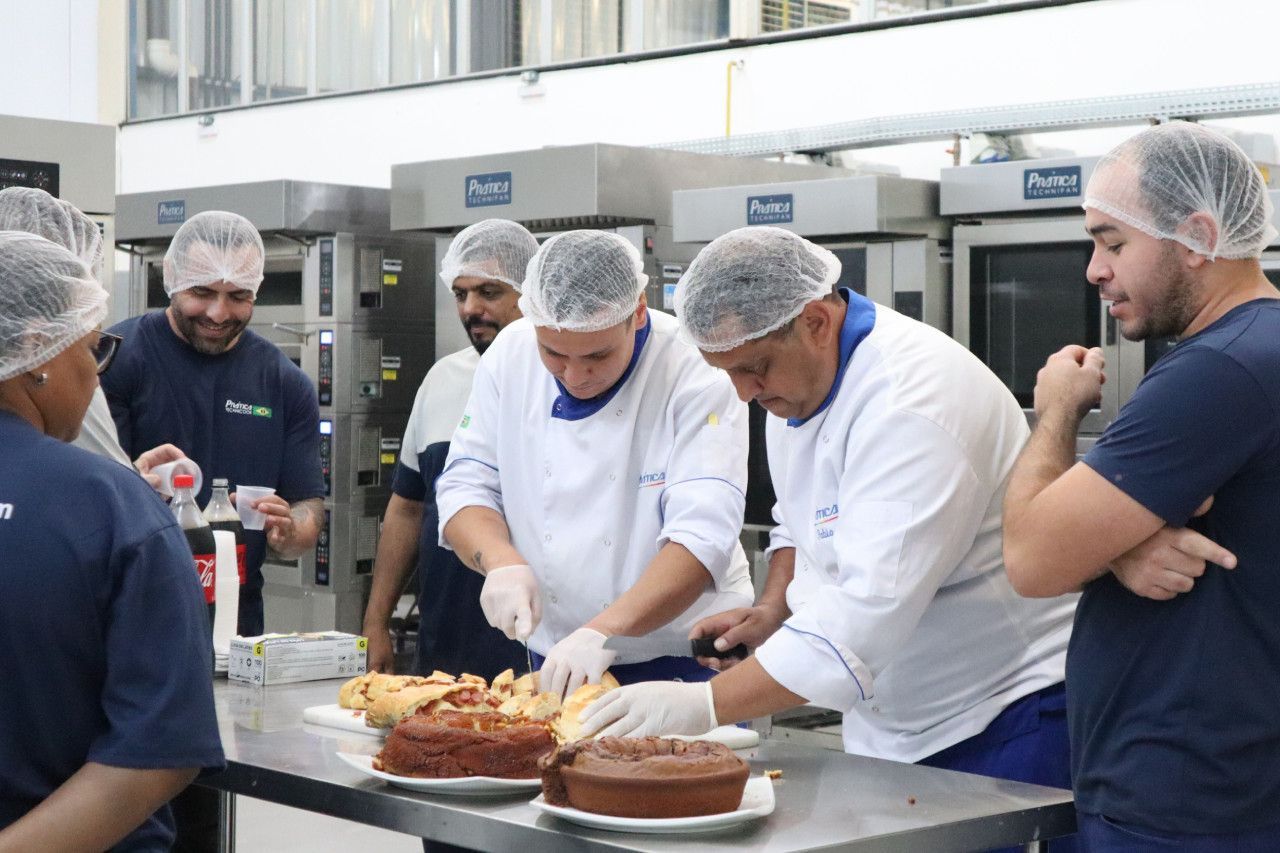 Um grupo de homens está em pé ao redor de uma mesa com bolos sobre ela.