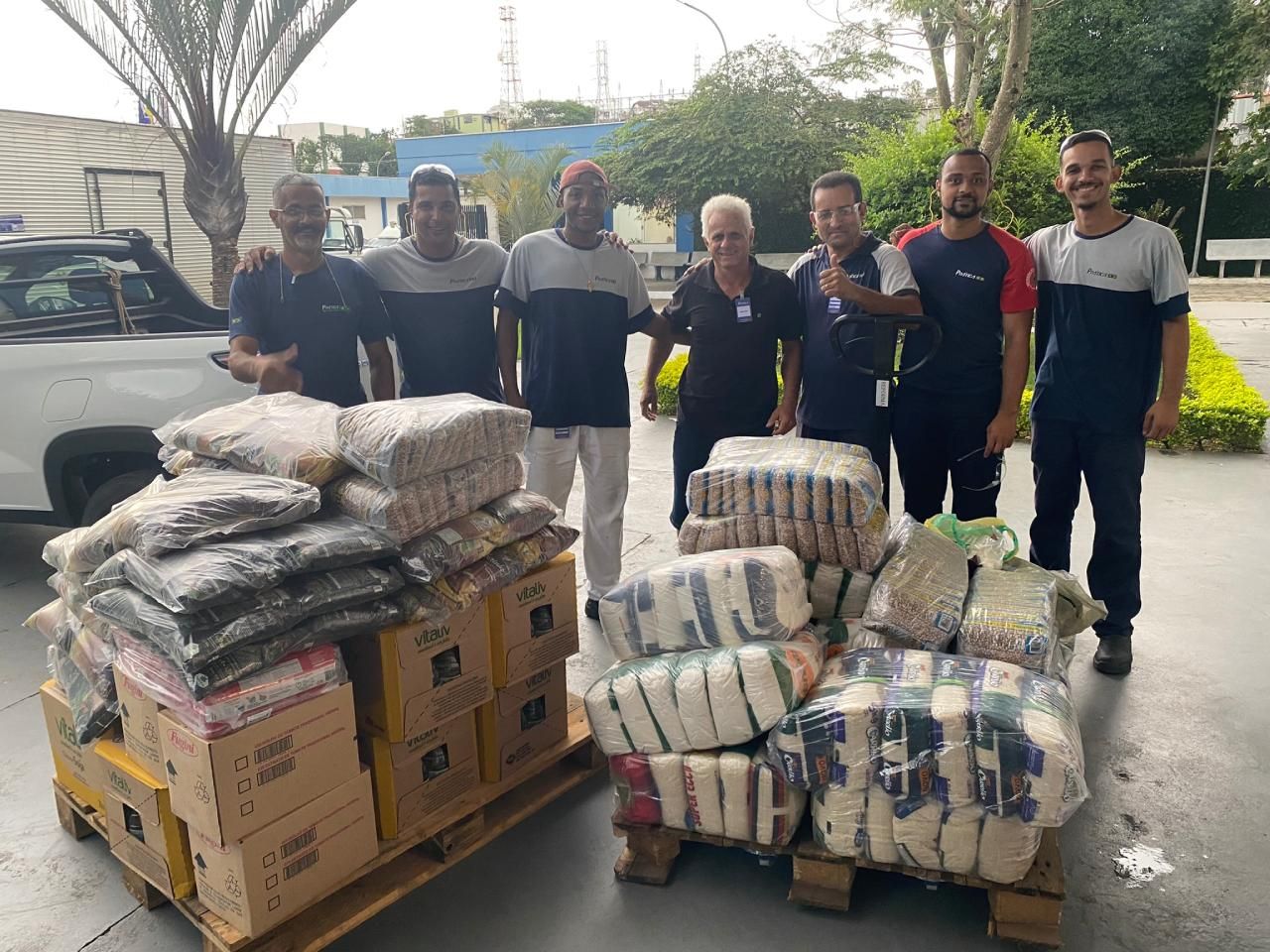 Um grupo de homens está de pé ao lado de um palete de comida.