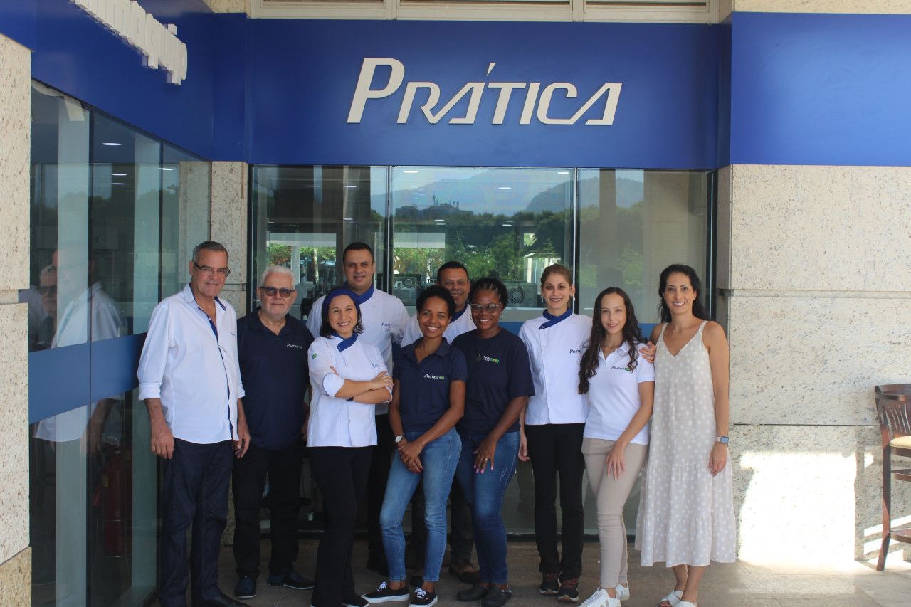 Um grupo de pessoas está posando para uma foto em frente a uma loja de pratica