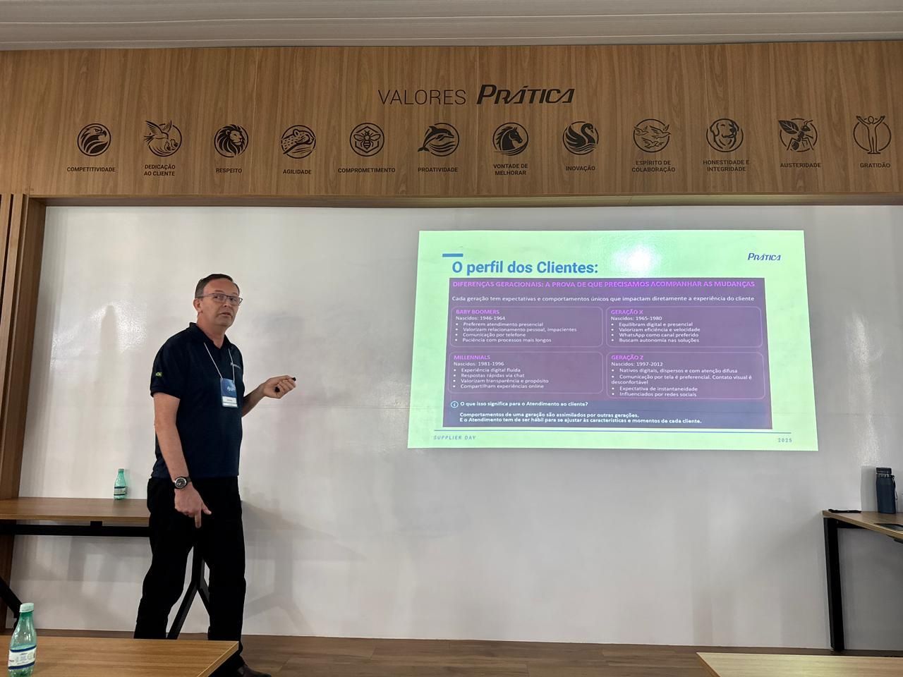 Um homem faz uma apresentação com uma tela de projeção. Ele aponta para a tela, em ambiente interno.