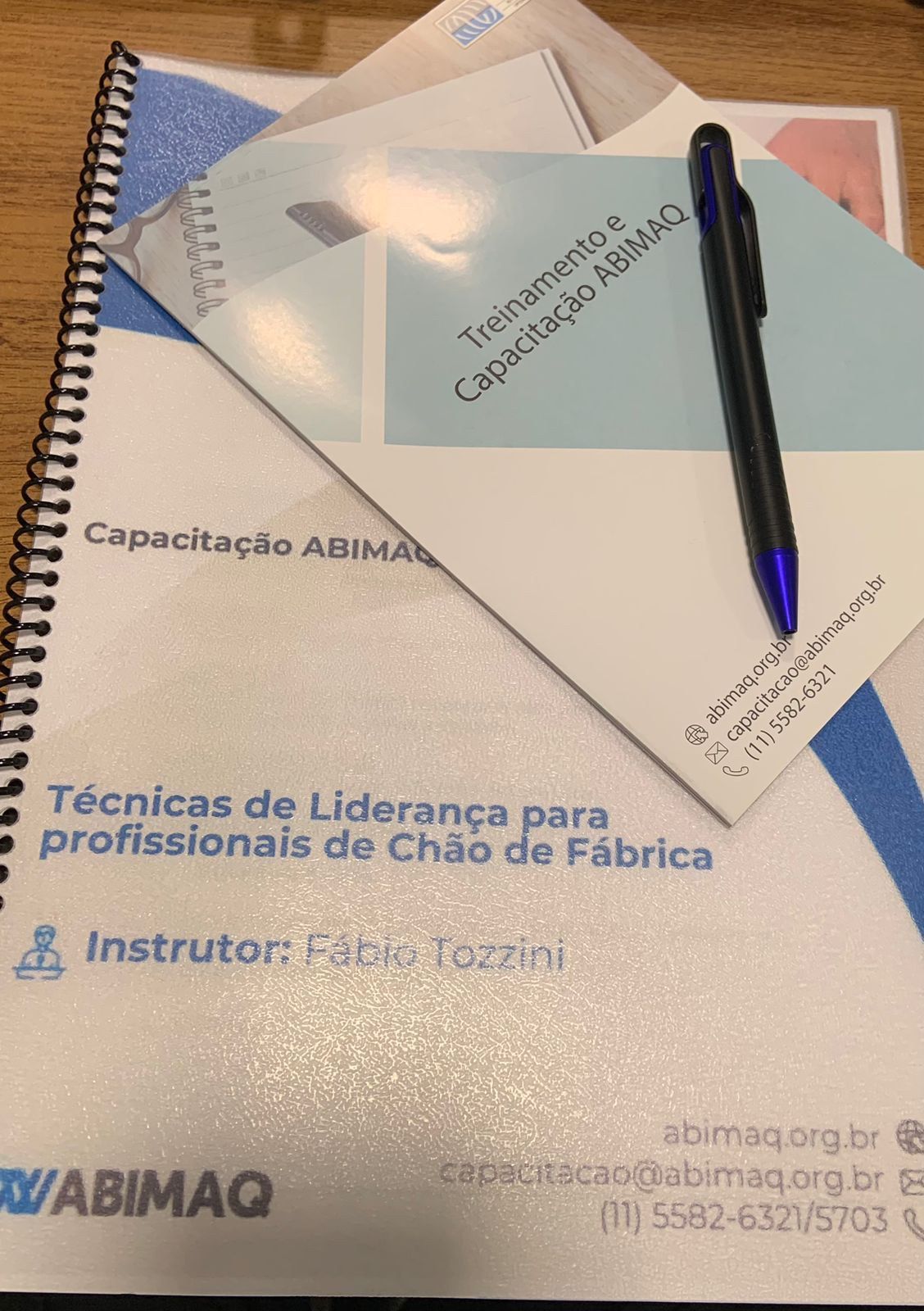 Uma caneta está em cima de um caderno sobre uma mesa.