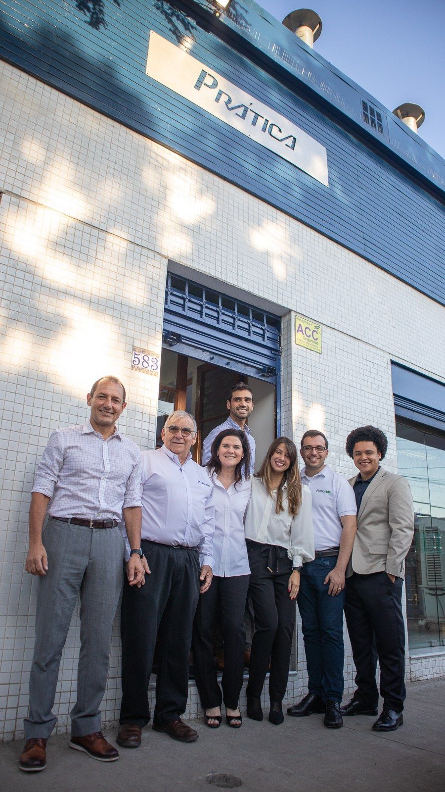 Um grupo de pessoas está posando para uma foto em frente a um prédio.