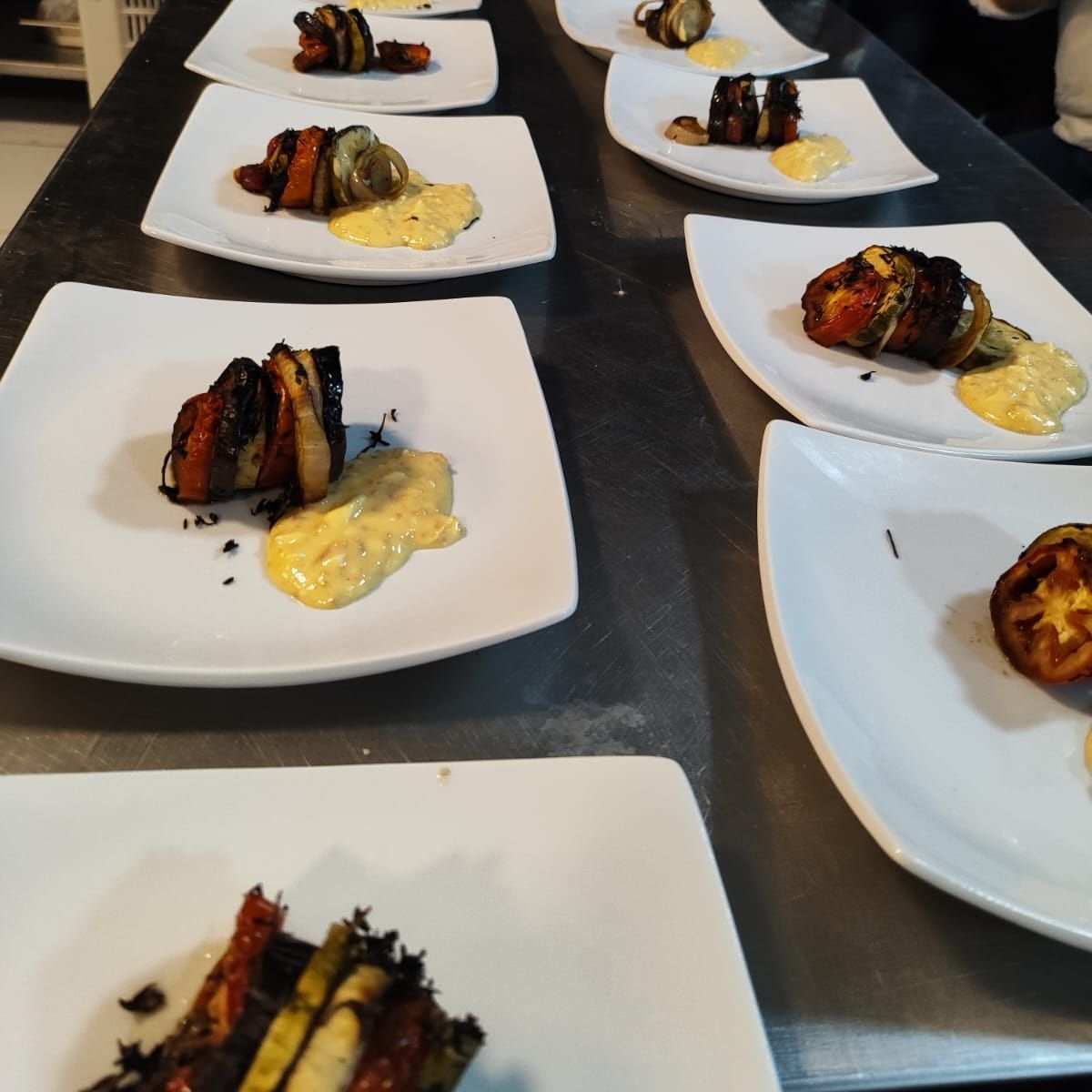 Uma fileira de pratos quadrados de comida em uma mesa