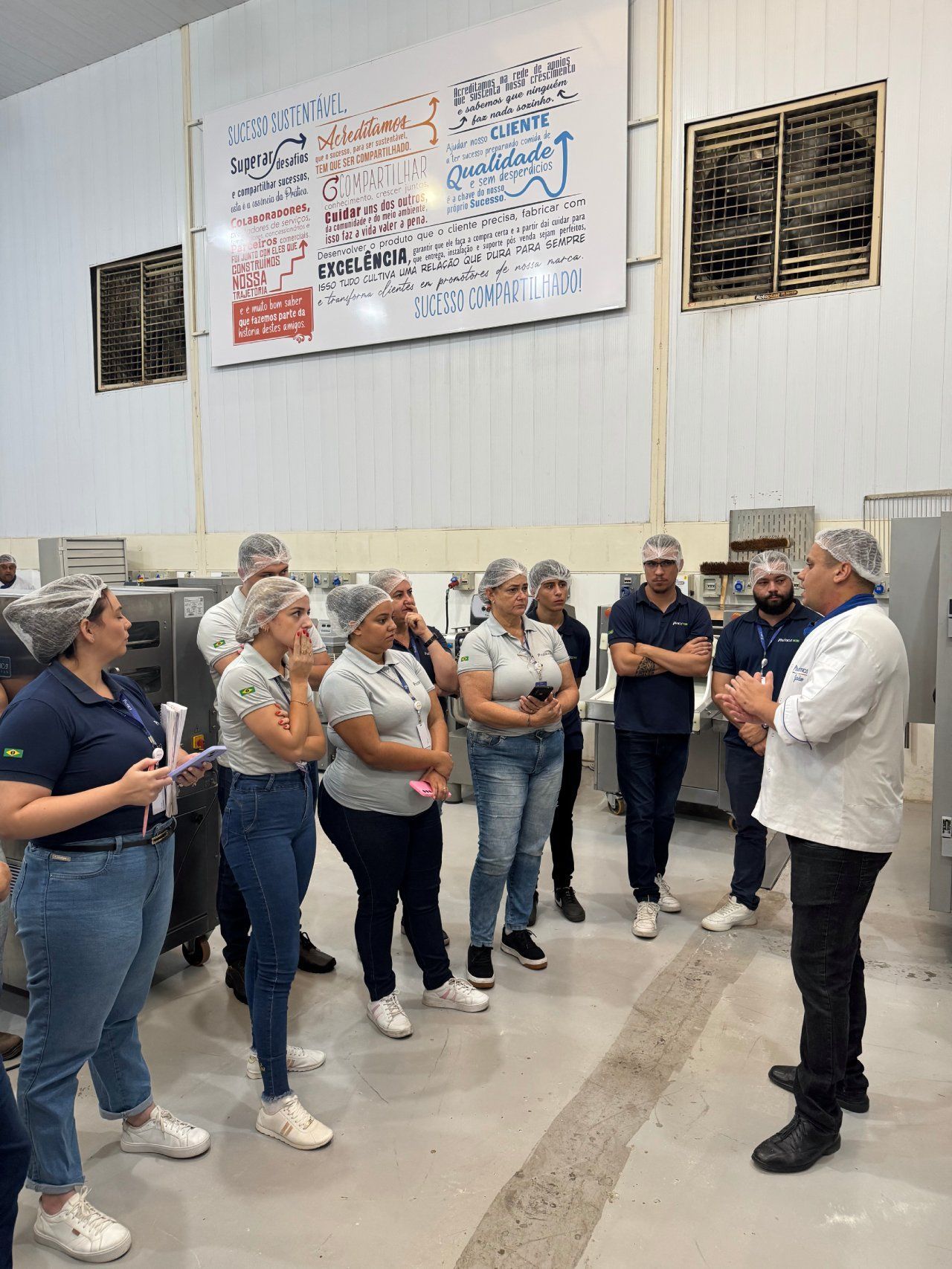 Um homem está conversando com um grupo de pessoas em uma fábrica.