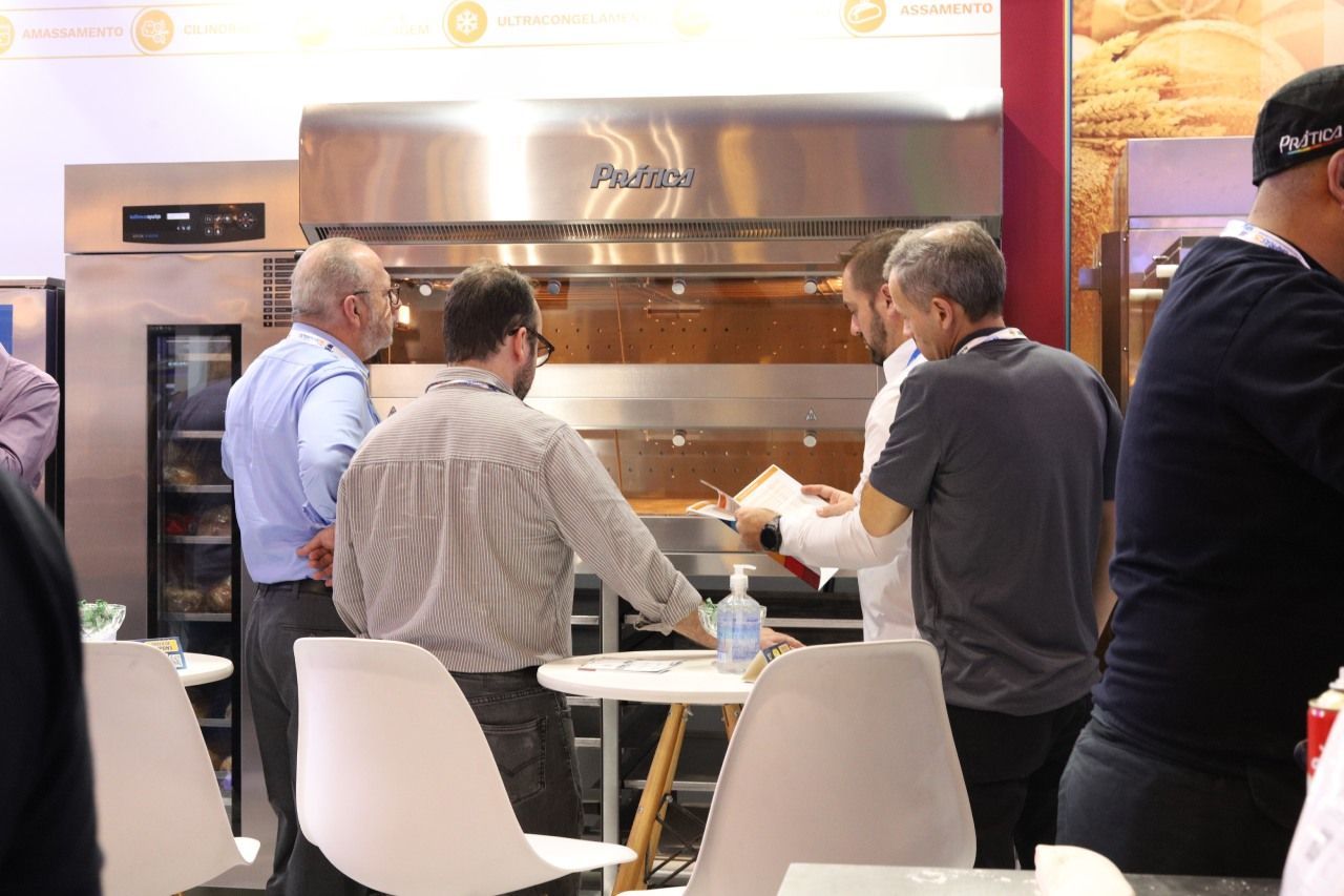 Um grupo de homens está em pé ao redor de uma mesa em frente a um forno.