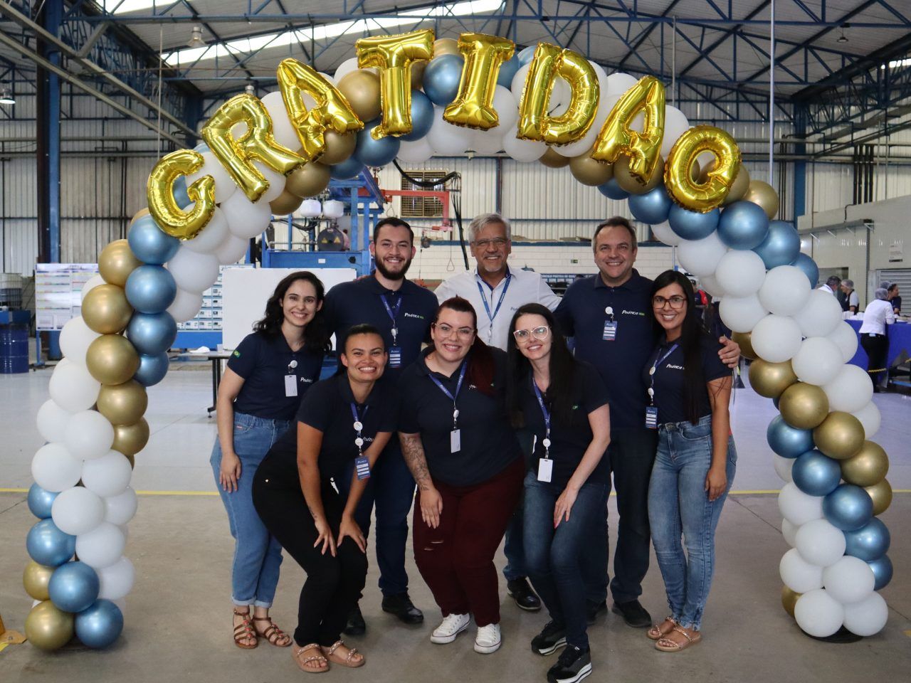 Um grupo de pessoas está posando para uma foto sob um arco de balões.