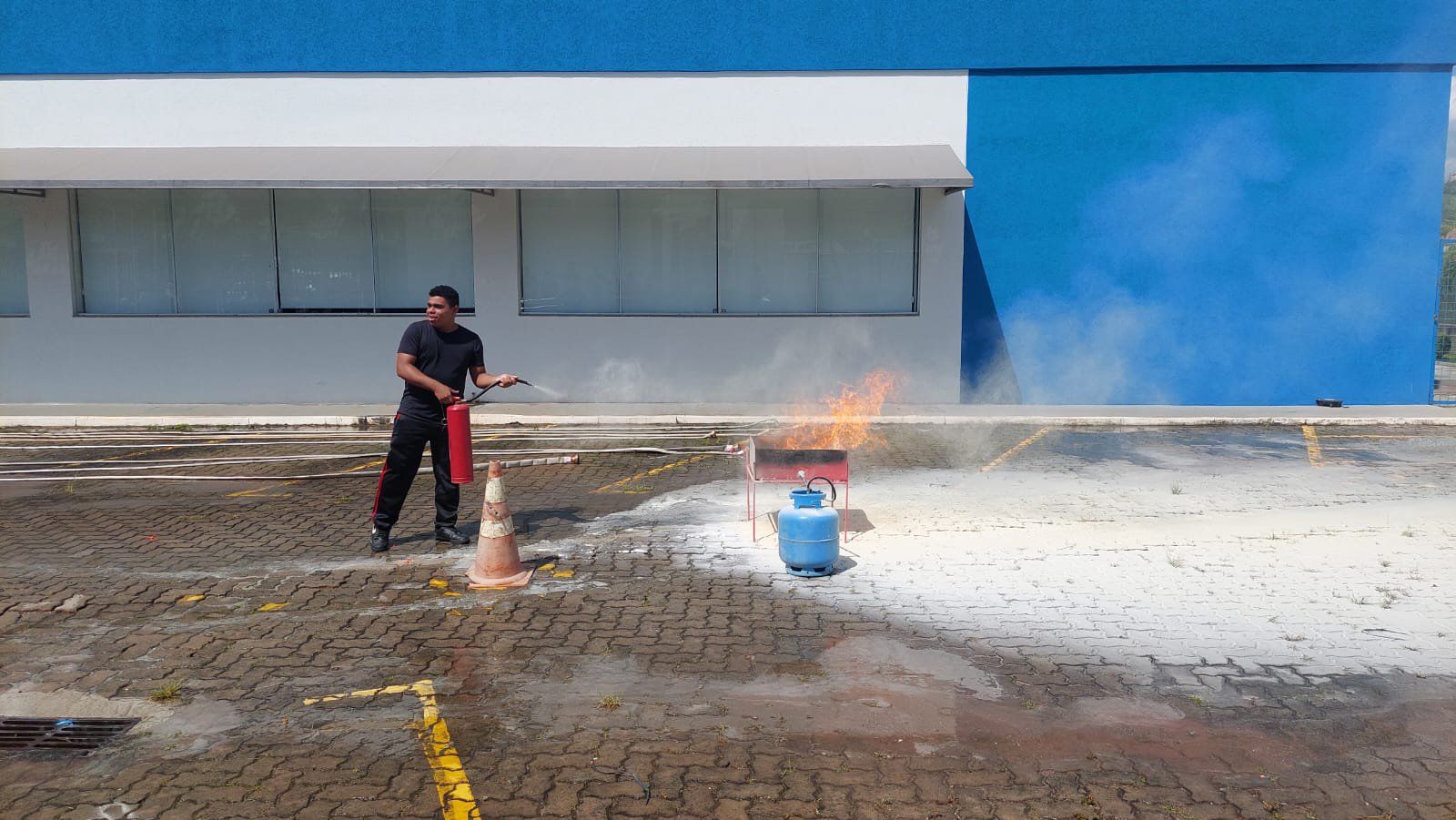 Um homem está usando um extintor de incêndio para apagar um incêndio em um estacionamento.