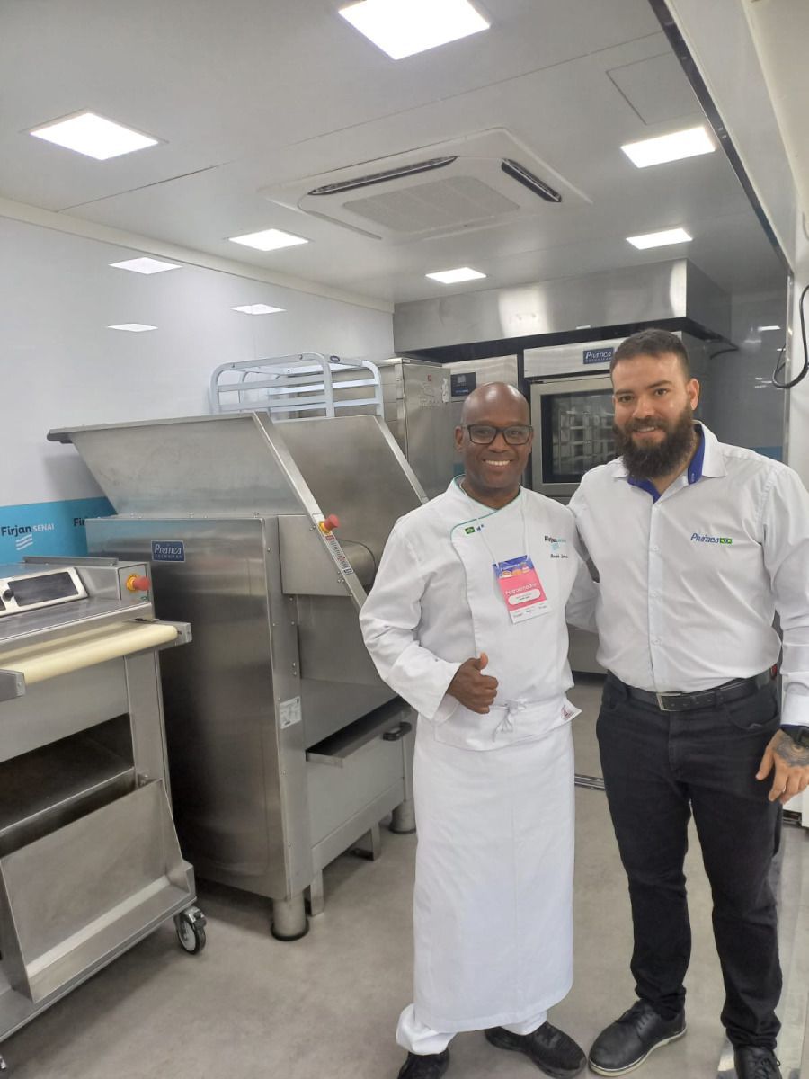 Dois homens estão parados um ao lado do outro em uma cozinha.